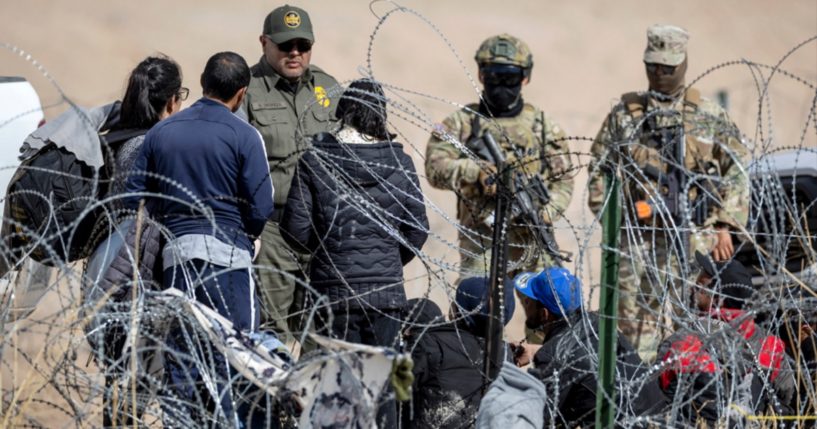 A Border Patrol agent speaks with illegal immigrants as Texas National Guard soldiers stand by Jan. 31 in El Paso, Texas.