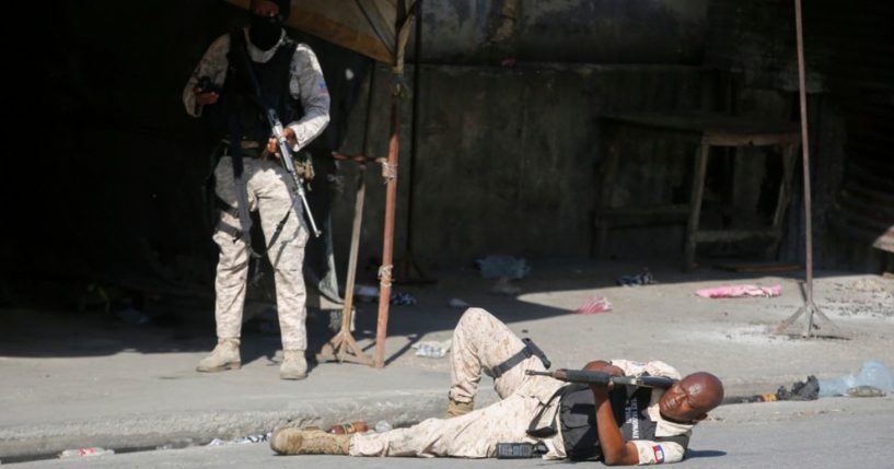 An officer aims his gun during clashes Friday with gang members in Port-au-Prince, Haiti.