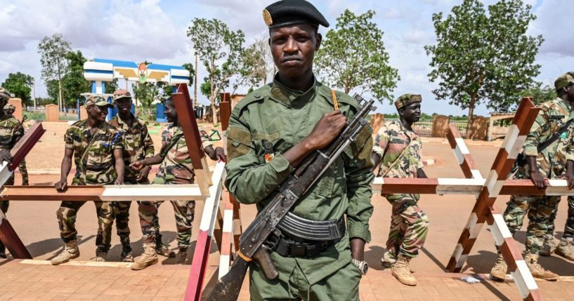 Officers of the Niger National Police and Nigerien soldiers stand guard as supporters of the Niger's National Council for the Safeguard of the Homeland gather at a demonstration outside the Niger and French airbases in Niamey, Niger, on Aug. 27.