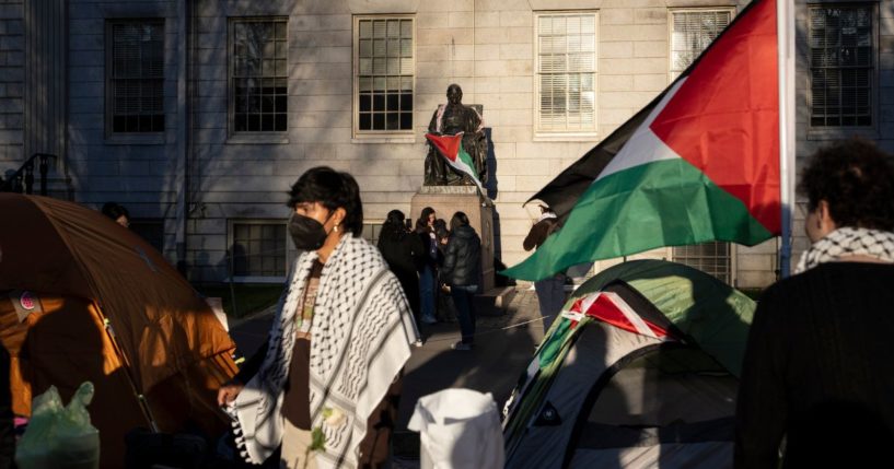 A student protester stands in front of the statue of John Harvard, the first major benefactor of Harvard College, draped in the Palestinian flag, at an encampment of anti-Israel demonstrators at Harvard University in Cambridge, Massachusetts on Thursday.