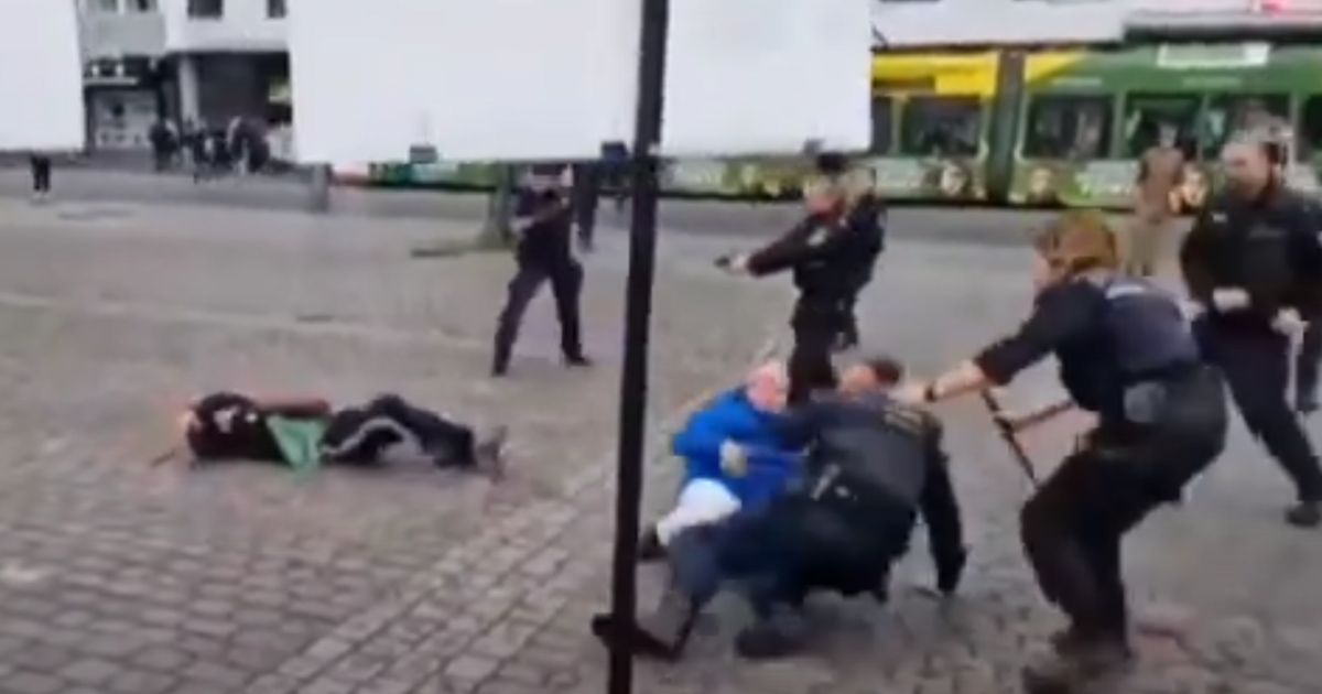 German police officers in Mannheim point their guns at a stabbing suspect on the ground, left, as others tend to wounded victims.