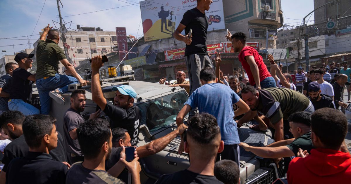 Palestinians gather around an Israeli army vehicle that Palestinian militants drove from Israel into Gaza following the Hamas terrorist attacks on Oct. 7.