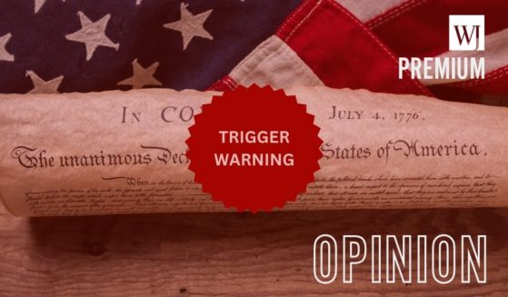 The United States Declaration of Independence is rolled into a scroll in front of the American flag, with "Trigger Warning" written over it.