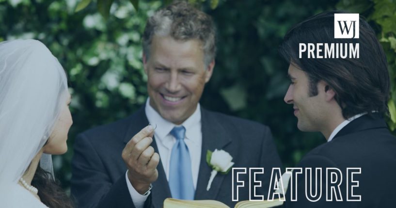 This stock image shows a man and a woman getting married, with a pastor holding up a wedding ring over a Bible.