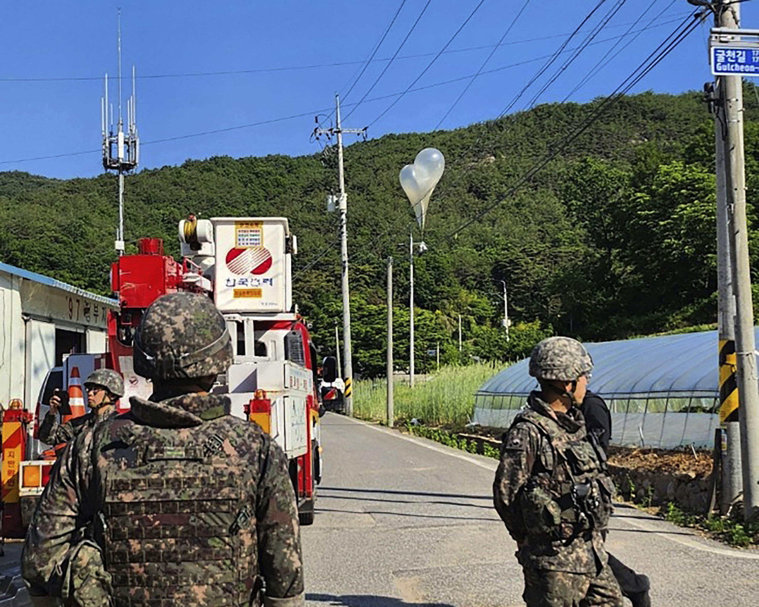 Balloons with trash, presumably sent by North Korea, hang on electric wires as South Korean army soldiers stand guard in Muju, South Korea, on Wednesday. North Korea launched more trash-carrying balloons toward the South after a similar campaign earlier in the week, according to South Korea's military, in what Pyongyang calls retaliation for activists flying anti-North Korean leaflets across the border.