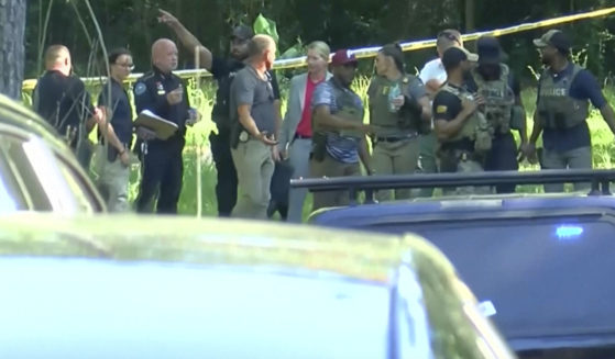 Law enforcement officers arrive at a wooded area on Thursday, June 13, 2024 in Jackson, Mississippi. A Louisiana woman was found dead in her home Thursday, and her two young daughters were abducted and found hours later in Mississippi -- One dead and the other alive, police said.