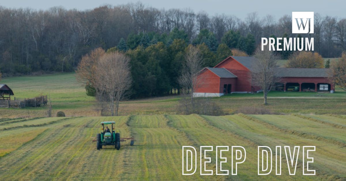 A farmer is seen in a file photo from 2020 driving a tractor across a field using a hay tedder to turn over dry hay at the Meach Cove Farms in Shelburne, Vermont.