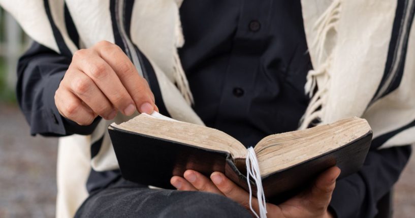 This image shows a close-up of a Jewish man wearing a tallit and reading the siddur on Shabbat.