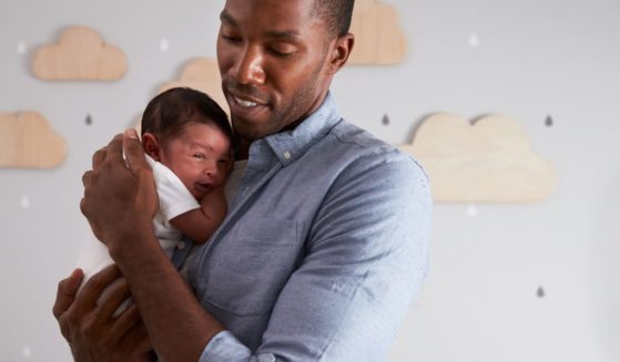 This image shows a father holding his newborn son in the nursery.
