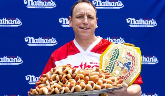 Competitive eater Joey Chestnut poses for photos with 76 hot dogs at a weigh-in before the Nathan's Famous July Fourth hot dog eating contest in New York on July 1, 2022.