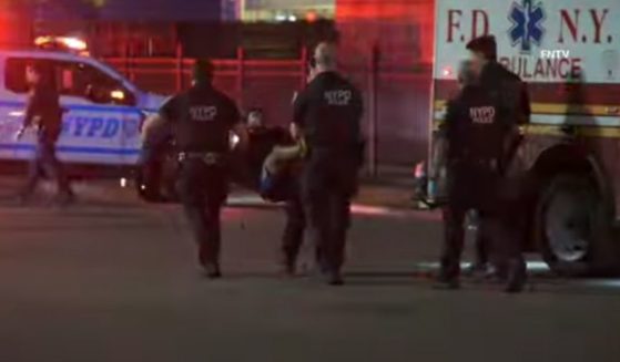 NYPD officers carry a suspect to an ambulance