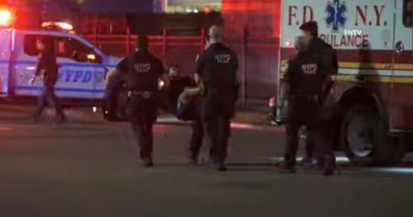 NYPD officers carry a suspect to an ambulance