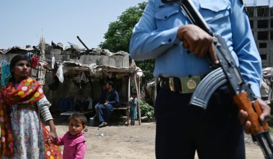 A Pakistani police officer stands guard as health workers engage in a door-to-door polio immunization campaign on the outskirts of Islamabad on April 26, 2019.