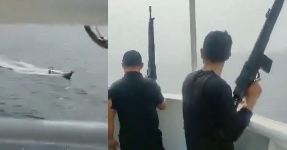 Armed guards watch an apparent kamikaze boat while onboard the M/V Tutor.