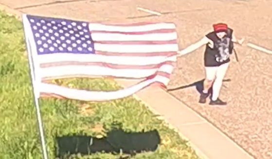 A woman curtsied as she ripped up an American flag surrounding police headquarters in Golden, Colorado on June 5.