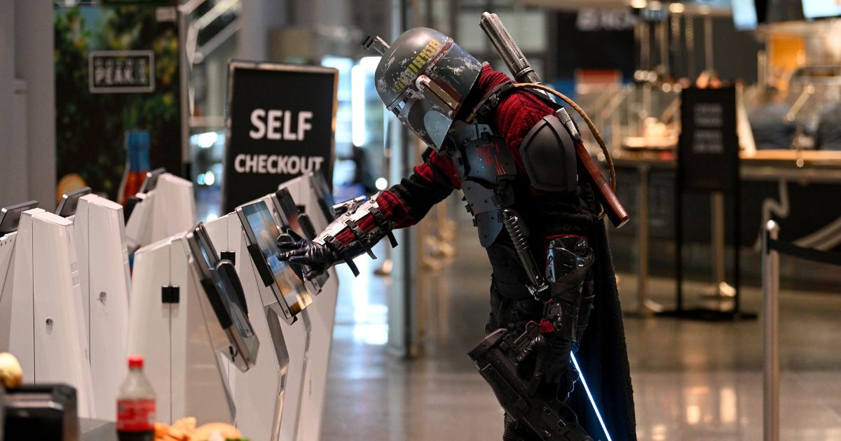 A cosplayer dressed as Boba Fett uses a self checkout machine during New York Comic Con 2022 on October 7, 2022 in New York City.