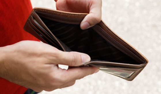 A stock photo shows a man opening an empty wallet.