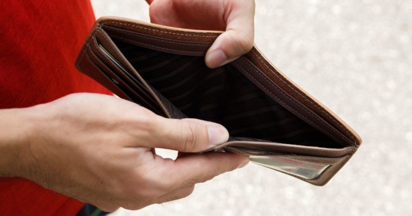 A stock photo shows a man opening an empty wallet.