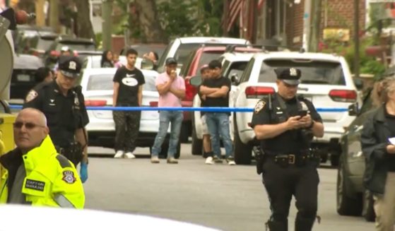 Police and onlookers are at the scene where a man was killed while crossing the street in Brooklyn, New York.