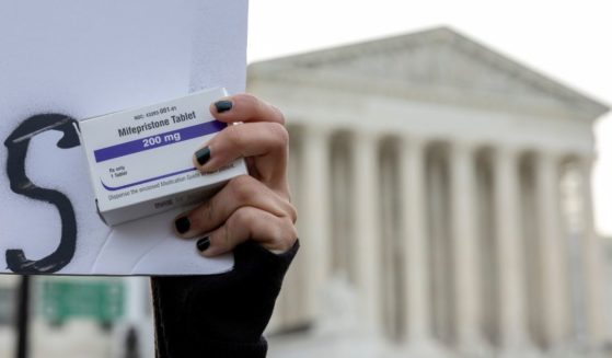 A pro-abortion activist holds a box of mifepristone pills while demonstrating outside the U.S. Supreme Court in Washington, D.C., on March 26.