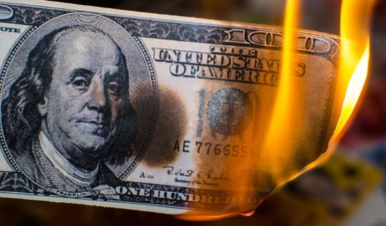 A stock photo shows a U.S. hundred-dollar bill on fire.