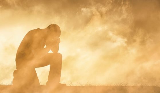 This image shows a man praying in an intense environment symbolizing the hardships of life.
