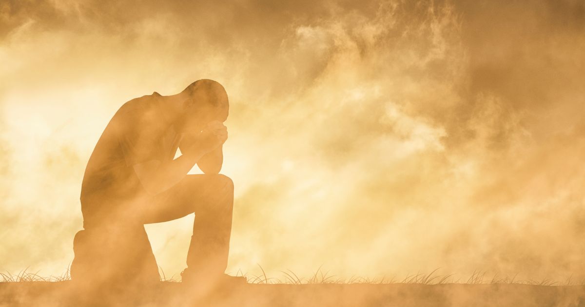This image shows a man praying in an intense environment symbolizing the hardships of life.