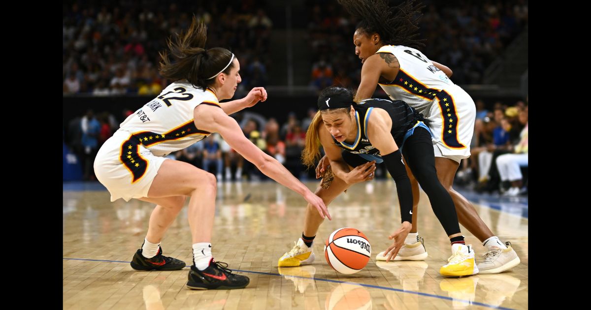 Caitlin Clark #22 of the Indiana Fever and Chennedy Carter #7 of the Chicago Sky battle for the lose basketball in the fist half at Wintrust Arena on June 23, 2024 in Chicago, Illinois.