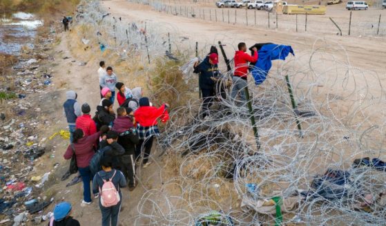 Seen from an aerial view, immigrant place clothing atop razor wire in order to climb over after crossing the border into El Paso, Texas from El Paso, Texas. Those who managed to get through the wire were then allowed to proceed for further processing by U.S. Border Patrol agents.