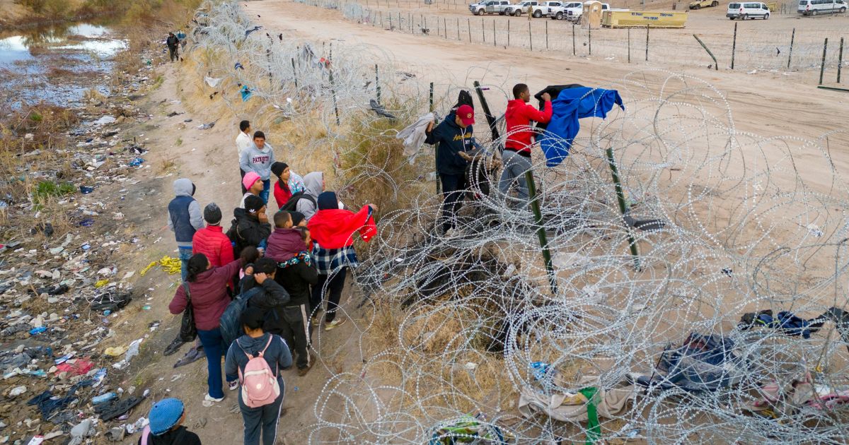 Seen from an aerial view, immigrant place clothing atop razor wire in order to climb over after crossing the border into El Paso, Texas from El Paso, Texas. Those who managed to get through the wire were then allowed to proceed for further processing by U.S. Border Patrol agents.