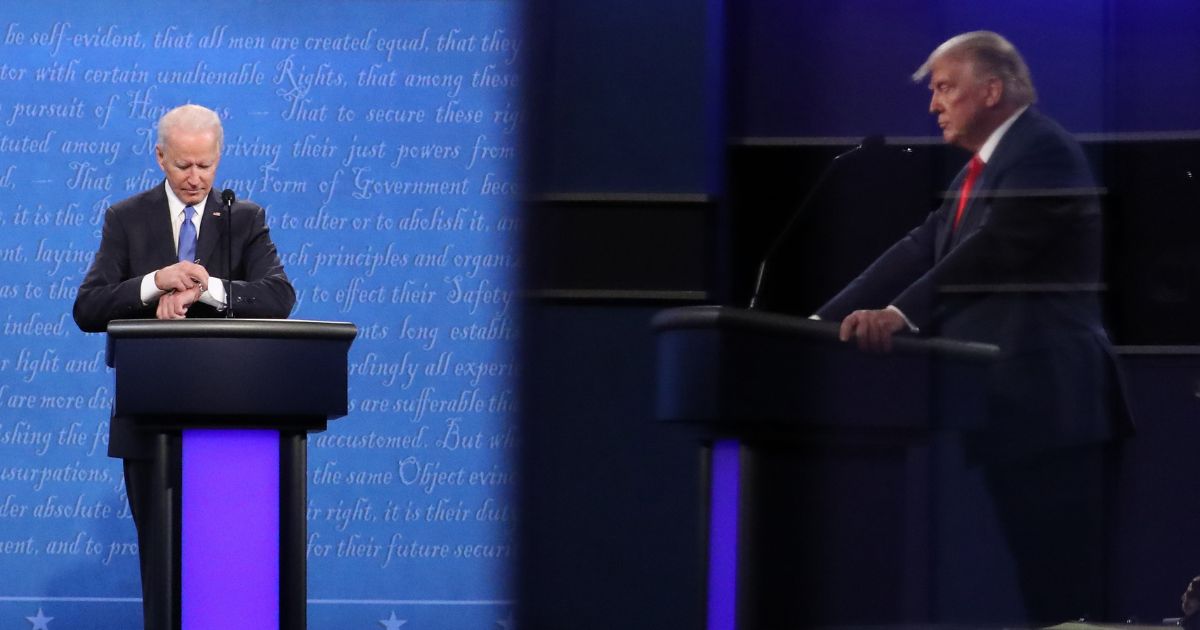 Democratic presidential nominee Joe Biden checks his watch during the final presidential debate against U.S. President Donald Trump (shown in reflection) at Belmont University on October 22, 2020 in Nashville, Tennessee.