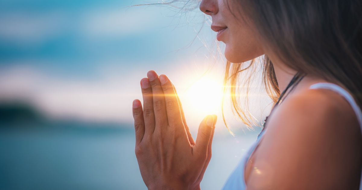 This image shows a woman praying with her hands together.