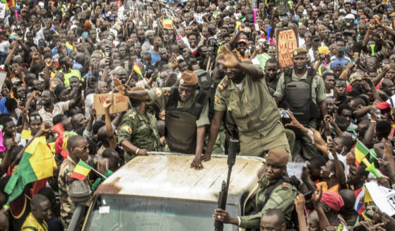 An unidentified representative of the junta waves from a military vehicle as Malians supporting the recent overthrow of President Ibrahim Boubacar Keita gathers to celebrate in the capital Bamako, Mali, on Aug. 21, 2020.