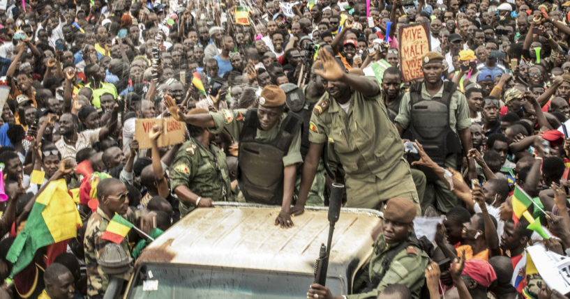 An unidentified representative of the junta waves from a military vehicle as Malians supporting the recent overthrow of President Ibrahim Boubacar Keita gathers to celebrate in the capital Bamako, Mali, on Aug. 21, 2020.