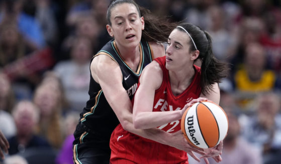 Indiana Fever's Caitlin Clark, right, makes a pass as New York Liberty's Breanna Stewart, left, defends during the first half of a WNBA basketball game in Indianapolis on Saturday.