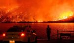 Law enforcement members watch as the Thompson fire burns over Lake Oroville in Oroville, California on Tuesday.