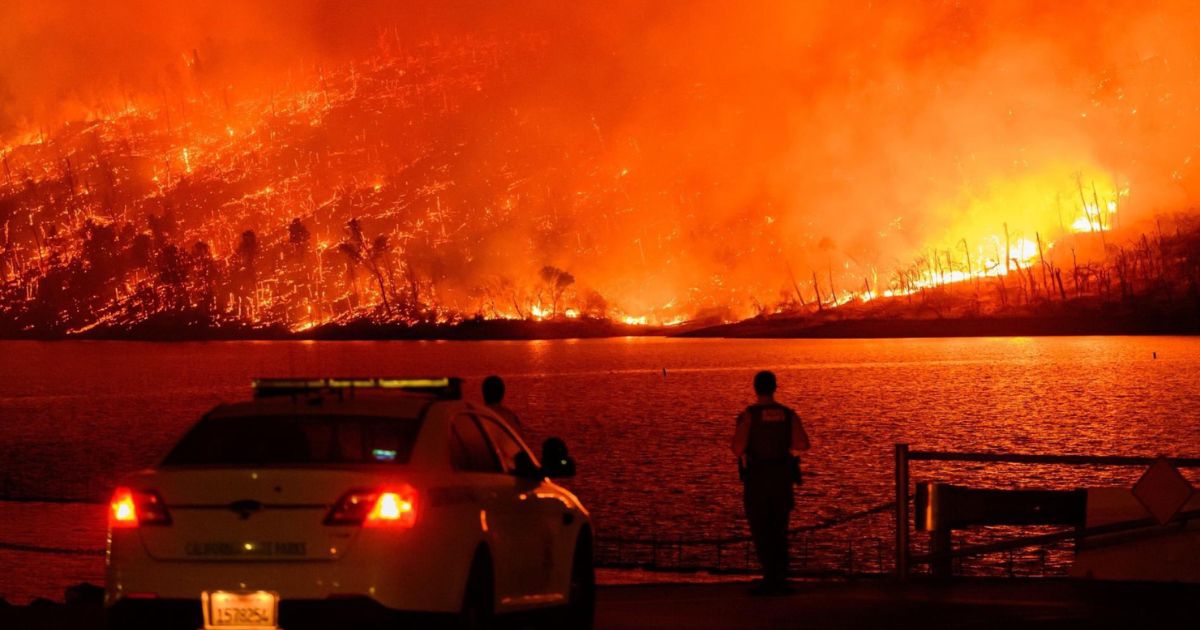 Law enforcement members watch as the Thompson fire burns over Lake Oroville in Oroville, California on Tuesday.