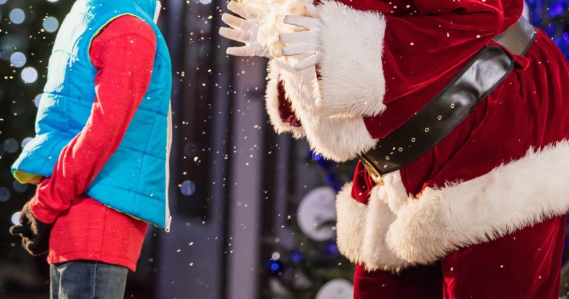 This stock image shows Santa Claus on the street talking to a young boy.