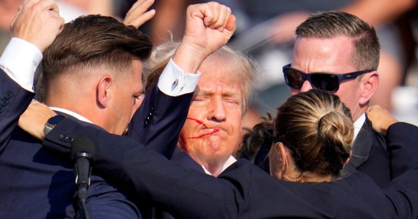 Former President Donald Trump holds up a fist while surrounded by Secret Service agents after an assassination attempt at a campaign rally in Butler, Pennsylvania, on Saturday.