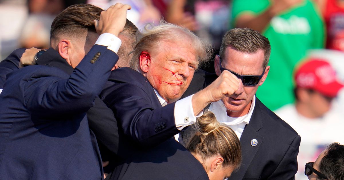 Former President Donald Trump raises his fist while being escorted off the stage after an assassination attempt at a campaign rally in Butler, Pennsylvania, on Saturday.