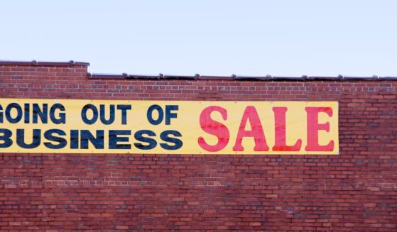 A stock photo shows a sign on the side of a brick building advertising a "Going out of business sale."