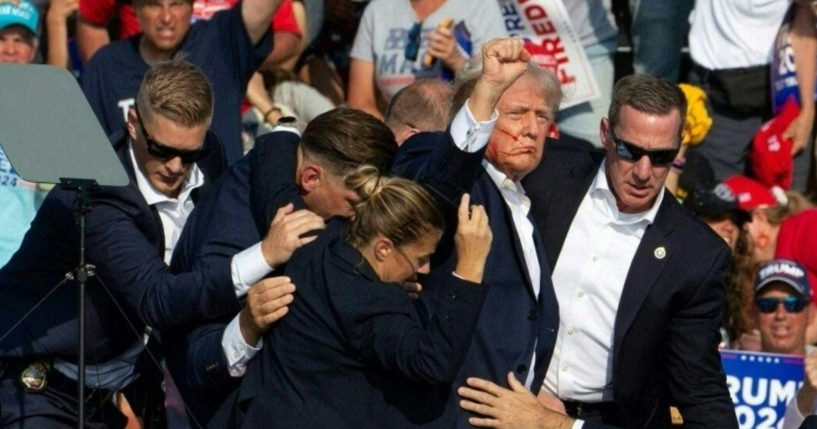 Republican candidate Donald Trump is seen with blood on his face surrounded by secret service agents as he is taken off the stage at a campaign event.