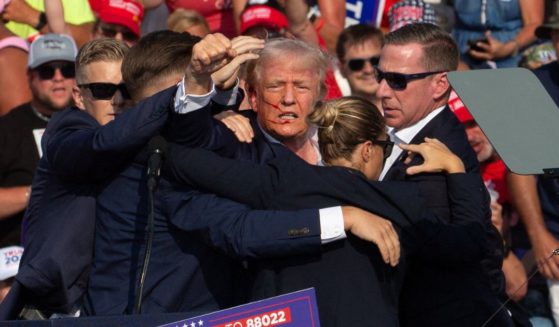 Republican candidate Donald Trump is seen with blood on his face surrounded by secret service agents as he is taken off the stage at a campaign event.