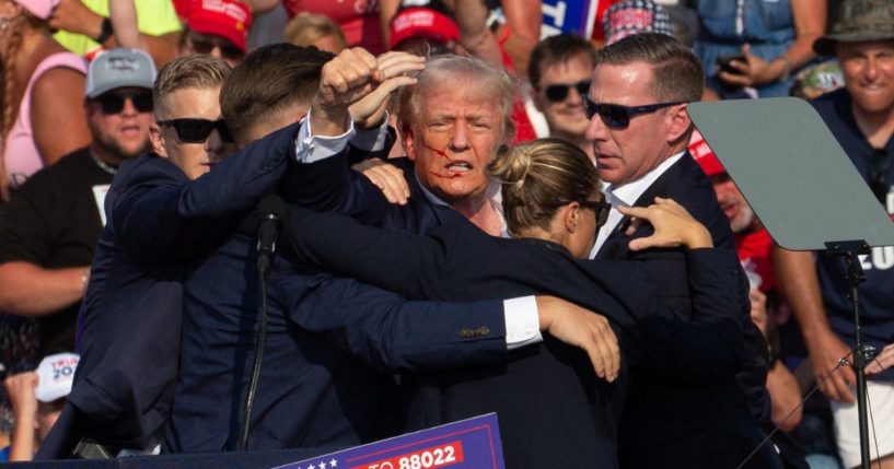 Republican candidate Donald Trump is seen with blood on his face surrounded by secret service agents as he is taken off the stage at a campaign event.