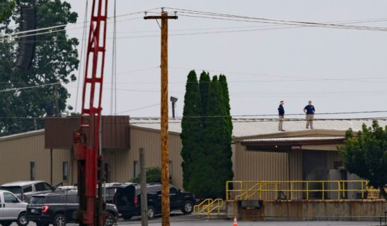 Two FBI investigators scan the roof of AGR International Inc, the building adjacent to the Butler Fairgrounds, from which alleged shooter Matthew Thomas Crooks fired at former President Donald J. Trump, in the aftermath of the attempted assassination at a campaign rally Saturday in Butler, Pennsylvania.