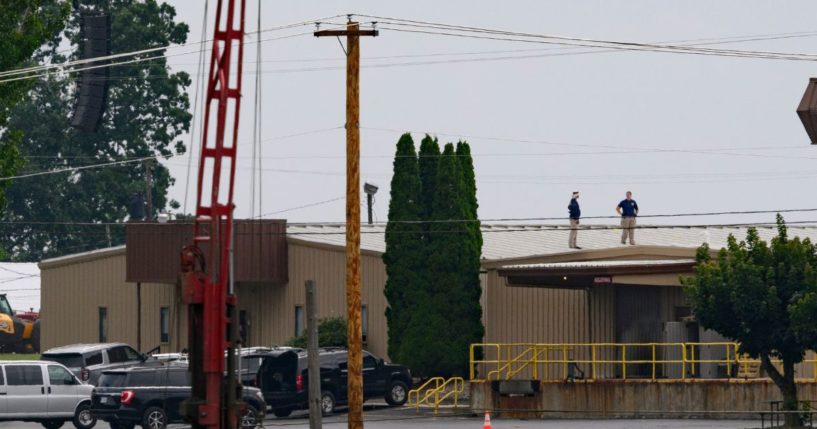 Two FBI investigators scan the roof of AGR International Inc, the building adjacent to the Butler Fairgrounds, from which alleged shooter Matthew Thomas Crooks fired at former President Donald J. Trump, in the aftermath of the attempted assassination at a campaign rally Saturday in Butler, Pennsylvania.