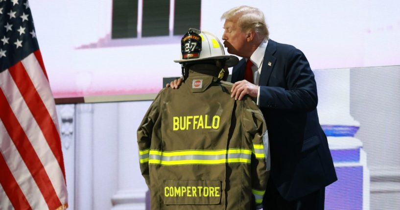 Republican presidential nominee and former President Donald Trump embraces the firefighter uniform of Corey Comperatore as he speaks on stage on the fourth day of the Republican National Convention at the Fiserv Forum in Milwaukee on Thursday.