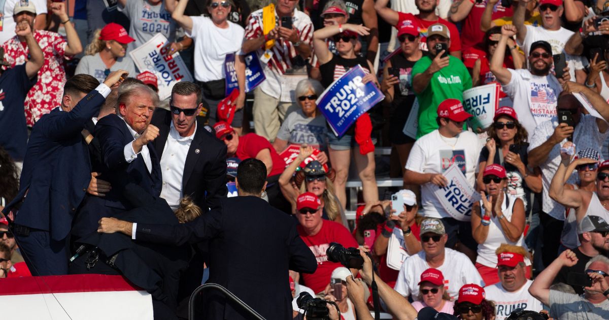 Republican presidential candidate Donald Trump is seen with blood on his face surrounded by Secret Service agents after he was shot during a campaign event in Butler, Pennsylvania, on Saturday.