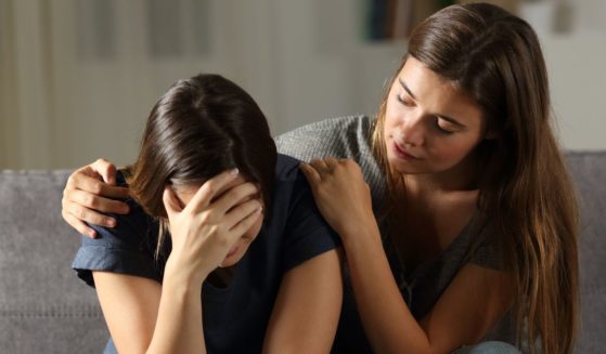 This image shows two young women. One is comforting the other who appears to be crying.