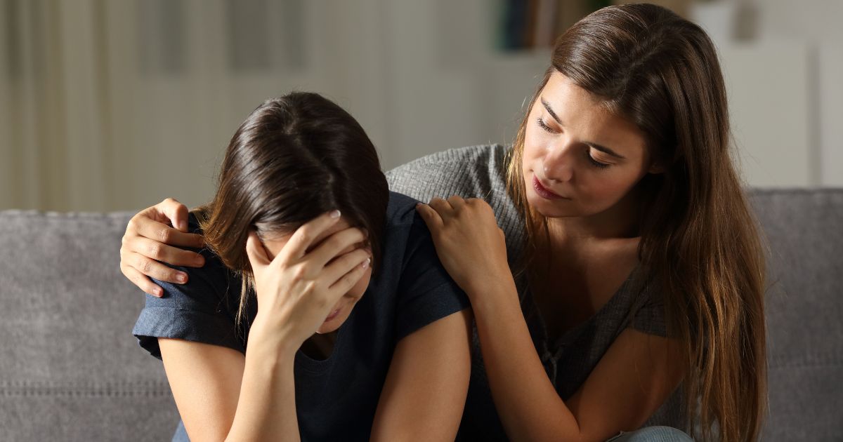 This image shows two young women. One is comforting the other who appears to be crying.